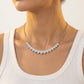 Model showing graduated pear cut moissanite curved smile necklace on collarbone.