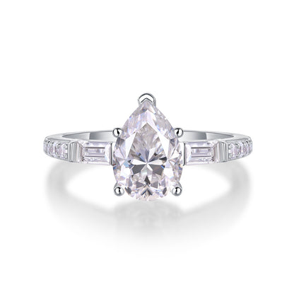 Pear cut moissanite engagement ring with baguette side accents and pave band on white background.