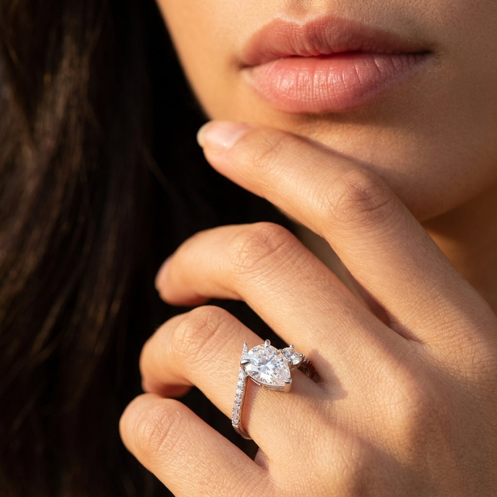 Close-up view of a model wearing pear cut moissanite toi et moi engagement ring.