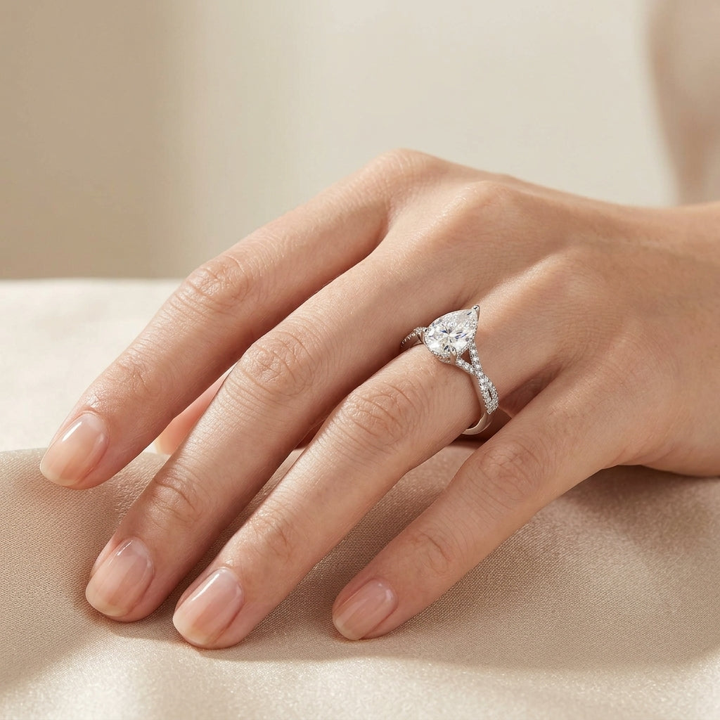Pear-cut moissanite twisted pavé engagement ring styled on hand, ideal for stackable ring trends