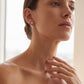 Model wearing pear and marquise cut diamond botanical leaf ear jacket earrings.
