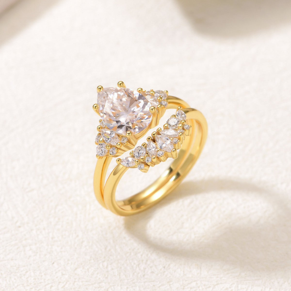 Perspective shot of gold pear cut moissanite cluster solitaire and curved crown stacking set.