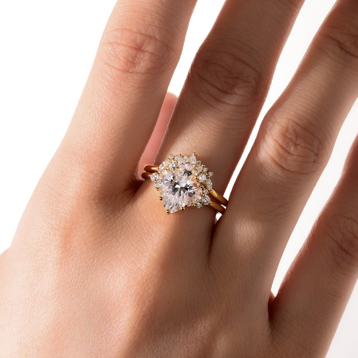 Full hand shot of model wearing pear cut moissanite cluster solitaire and curved crown ring set.