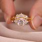 Close-up view of gold pear cut cluster solitaire with matching curved crown band held in hand.