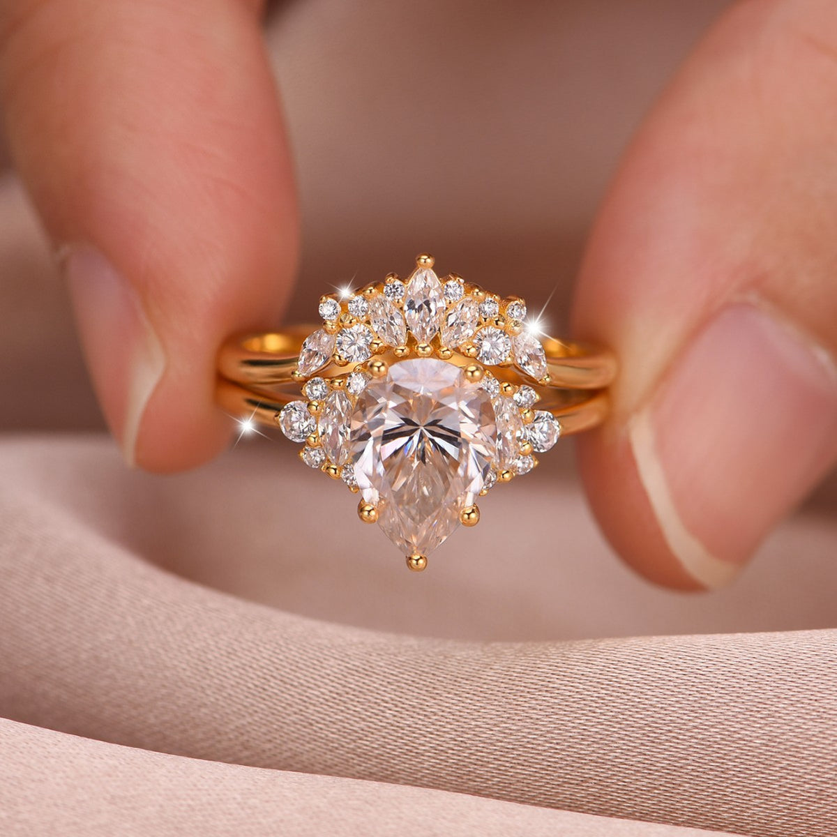 Close-up view of gold pear cut cluster solitaire with matching curved crown band held in hand.