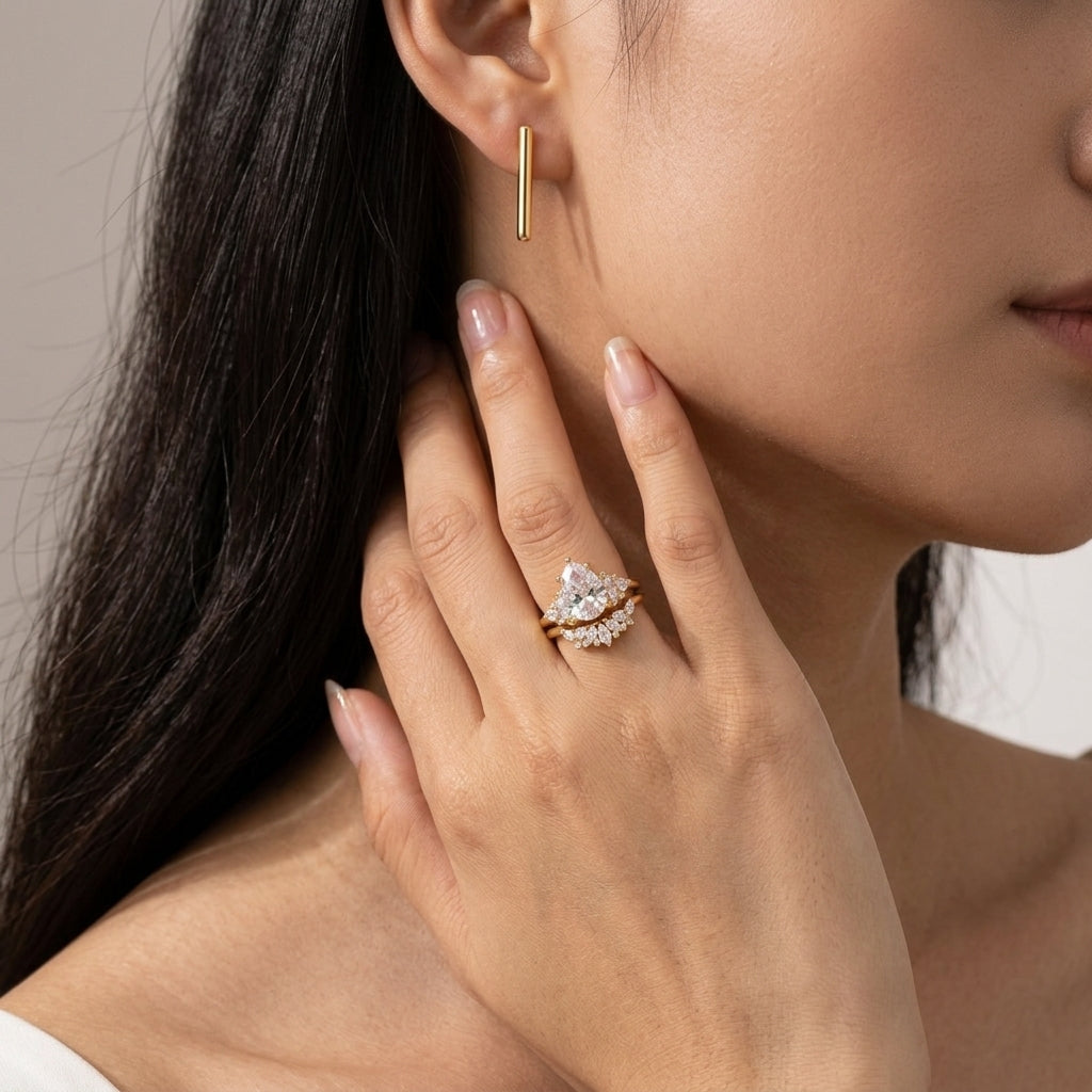 Model wearing pear cut moissanite cluster solitaire ring set with curved crown band.