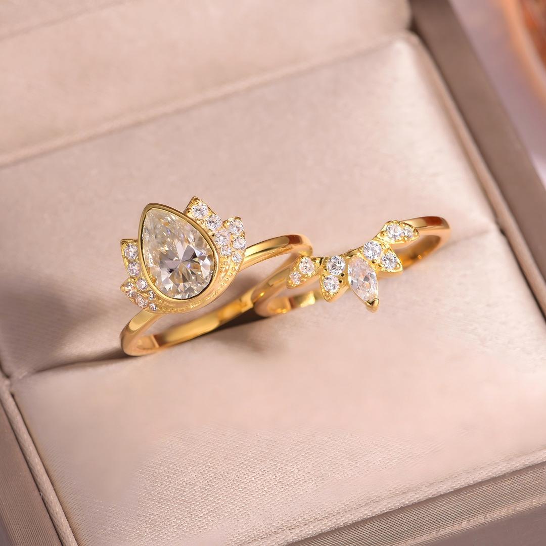 Angled view of gold pear cut moissanite lotus halo and sunburst crown ring set in box.