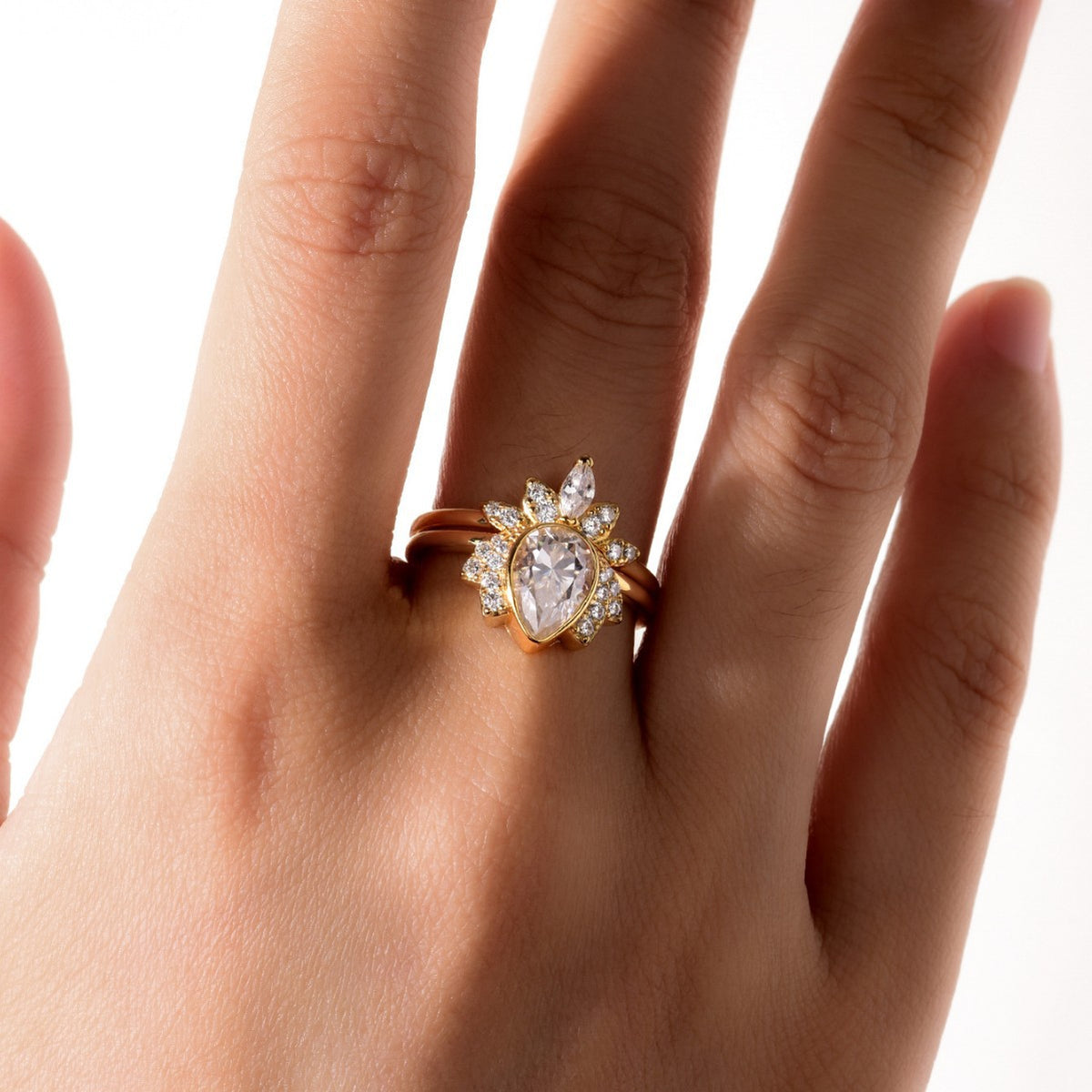 Model wearing pear cut moissanite lotus halo ring set with sunburst crown band.