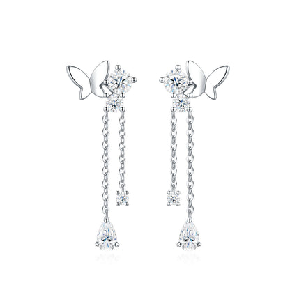 Symmetrical studio display of platinum plated butterfly moissanite dangle earrings with dual tassel chains and pear cut drop.