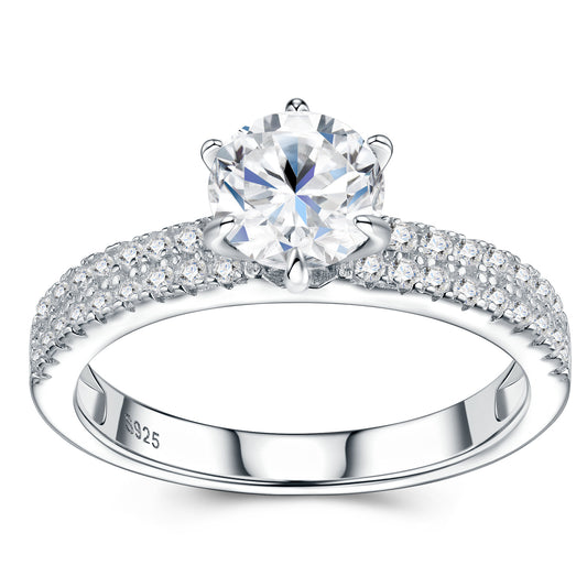 Symmetrical studio view of a platinum plated round cut moissanite solitaire ring with double row pave shank and six-prong mount.