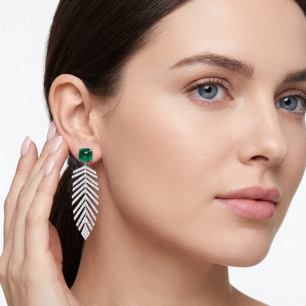 Side profile lifestyle view of an elegant model wearing classic emerald botanical feather drop earrings.