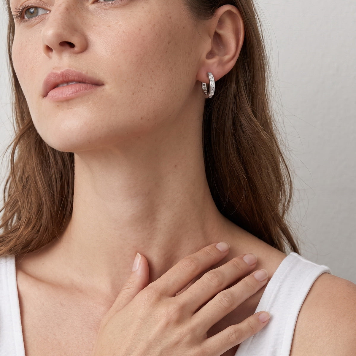 Model wearing princess cut moissanite channel set huggie hoop earrings