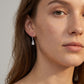 Model wearing princess cut two-stone dangle earrings with pavé line French wire.