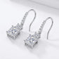 Angled flat lay view of princess cut two-stone dangle drop earrings with pavé hook.