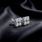 Side-angle view of quad moissanite cluster stud earrings showing posts on dark silk background.