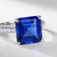 Macro close-up shot capturing the intense stone fire and step-cut facets of the square blue sapphire ring.