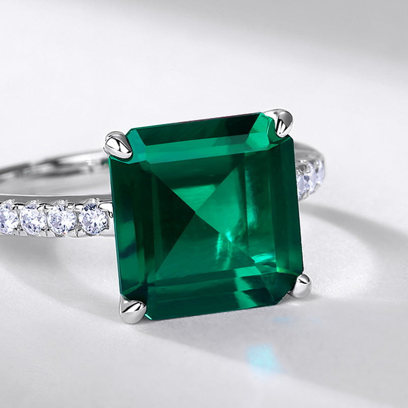 Ring with a large green gemstone and smaller diamonds on a light gray background