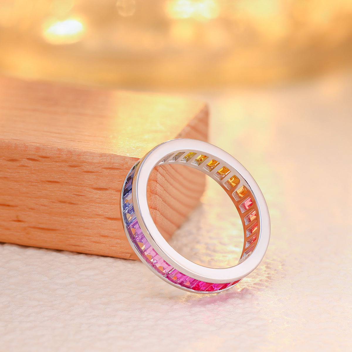 Angled view of rainbow baguette cut multi-color gemstone channel set band.