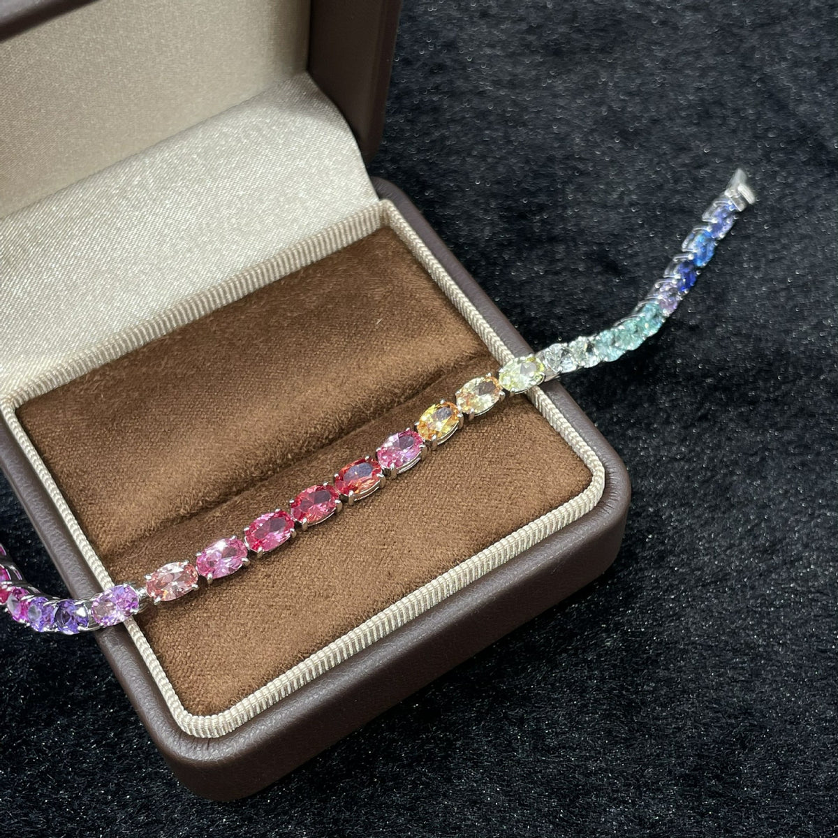 Curved angle display of rainbow oval cut multi-color gemstone tennis bracelet.