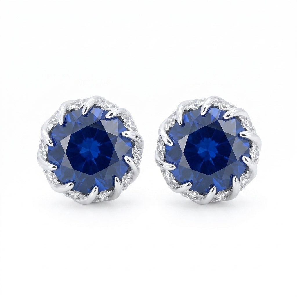 Front view of classic round-cut brilliant blue sapphire stud earrings on white backdrop.