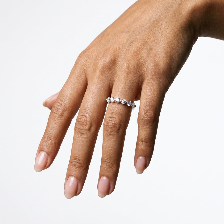 Full hand view of model wearing round brilliant diamond simulant 7-stone anniversary band.