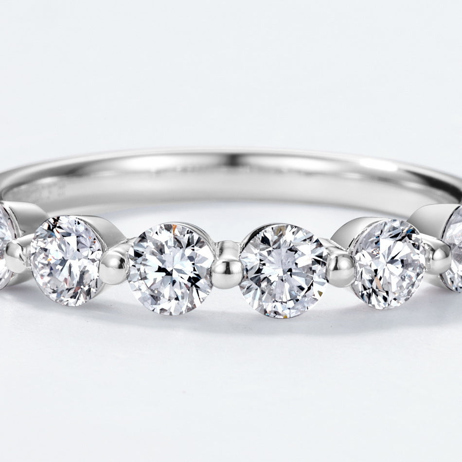 Extreme close-up showing shared-prong setting of round brilliant diamond simulant wedding band.