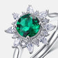 Silver ring with a green gemstone and clear teardrop-shaped stones on a white background