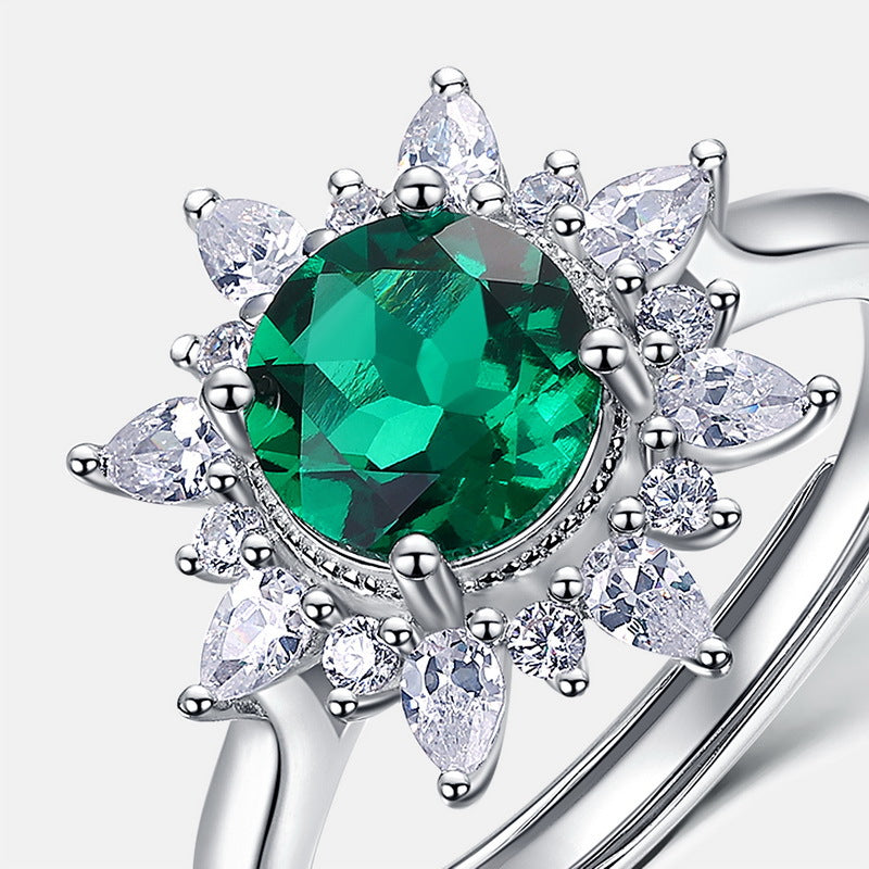 Silver ring with a green gemstone and clear teardrop-shaped stones on a white background