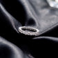 Side profile view showing shared prong setting of round lab grown diamond eternity ring on black silk