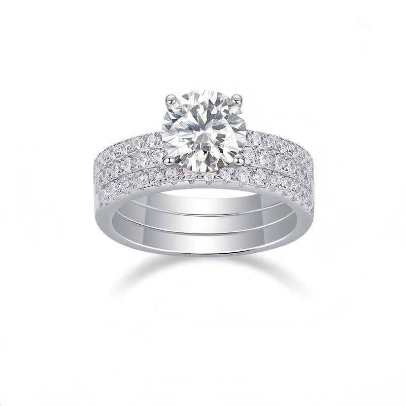 Round cut moissanite engagement ring with triple row pave stacking wedding band set on white background.