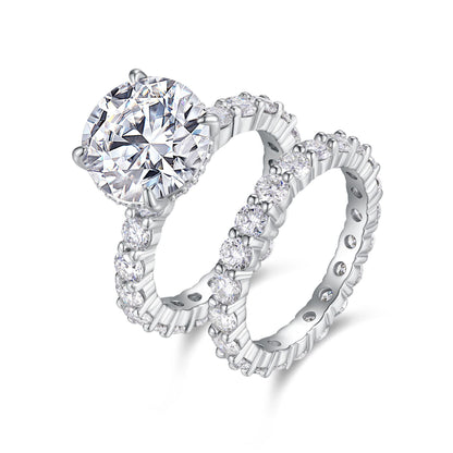 Round cut moissanite hidden halo engagement ring with matching shared prong eternity wedding band set on white background.