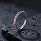 Silver round cut rainbow gradient pave eternity band ring on textured black volcanic stone surface