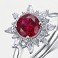 Silver ring with a red gemstone and diamond accents on a white background