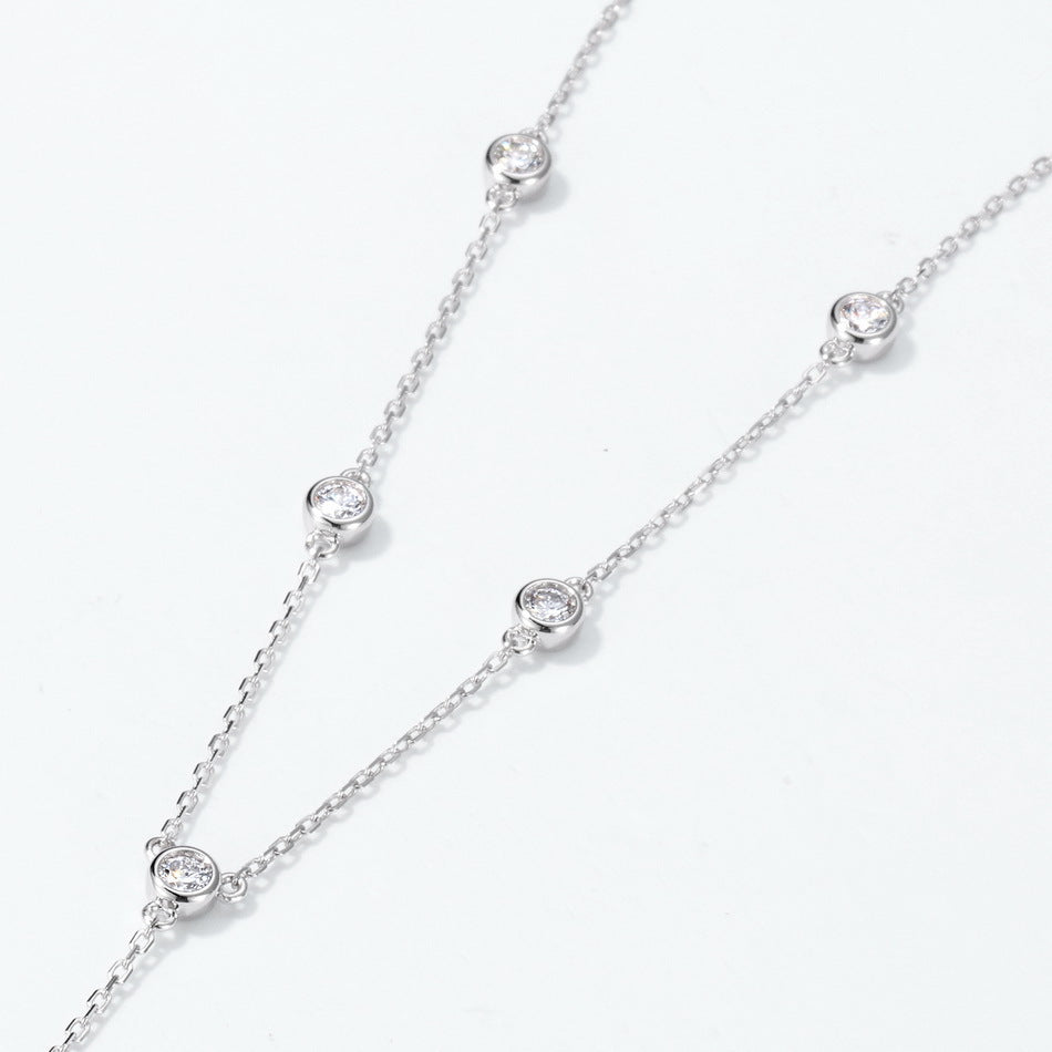 Close-up view of round diamond bezel-set stations along delicate cable chain.