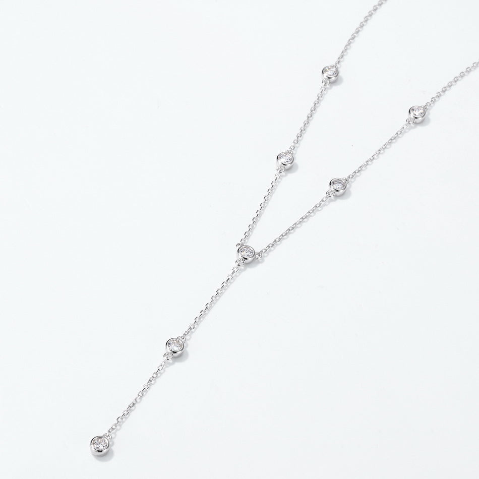 Angled view of round diamond bezel-set station Y-necklace on white background.