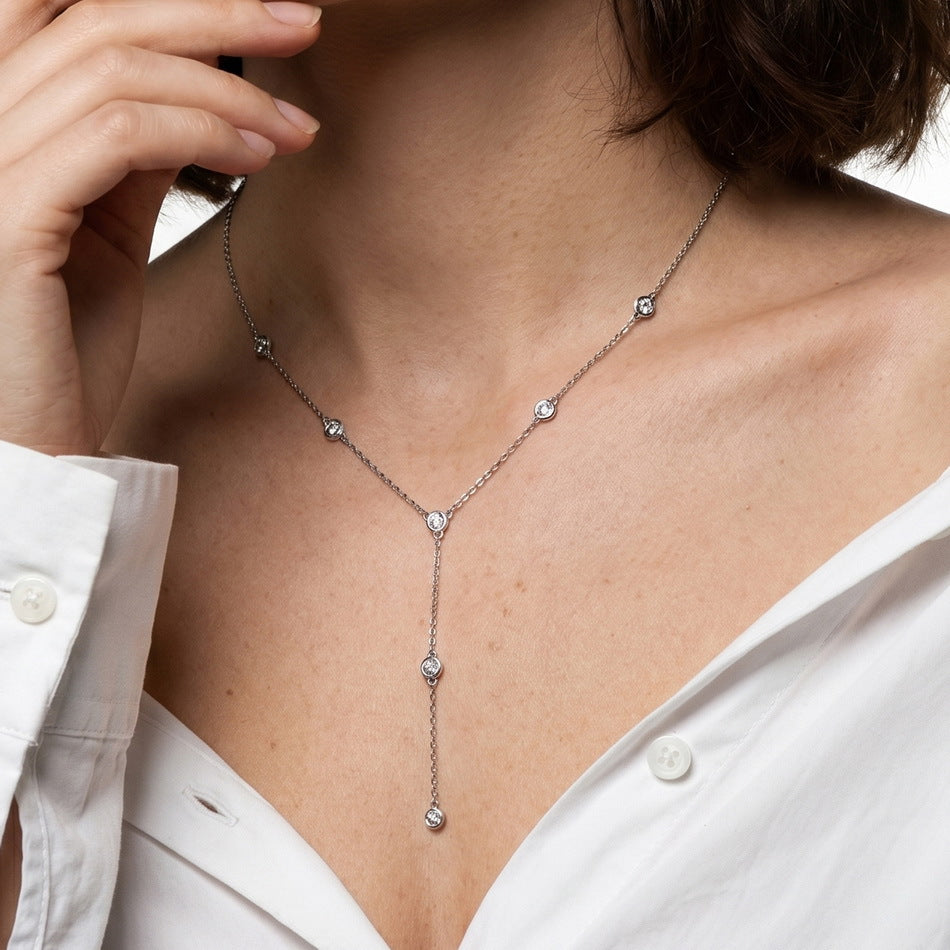 Model wearing round diamond bezel-set station Y-necklace with unbuttoned white shirt.