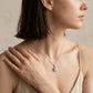 Model wearing round diamond cushion halo pendant necklace on collarbone.