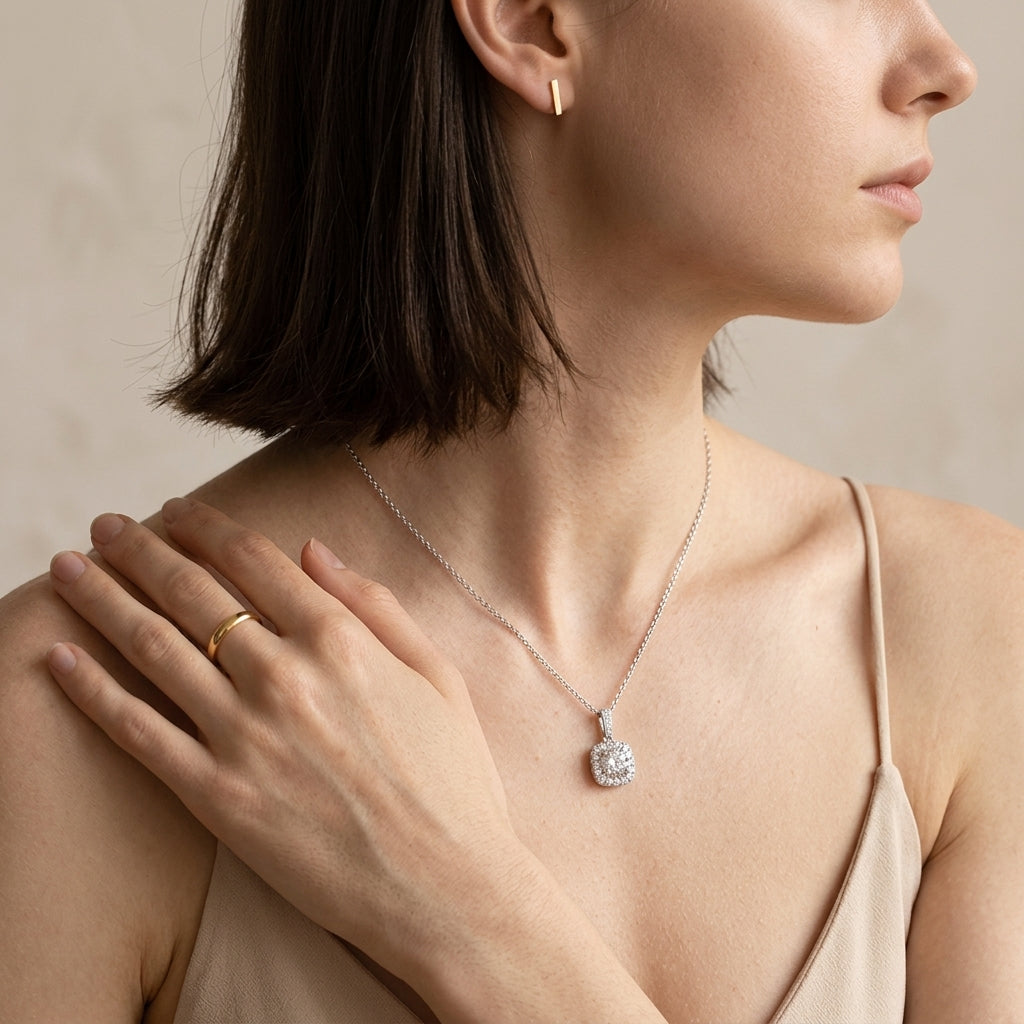 Model wearing round diamond cushion halo pendant necklace on collarbone.