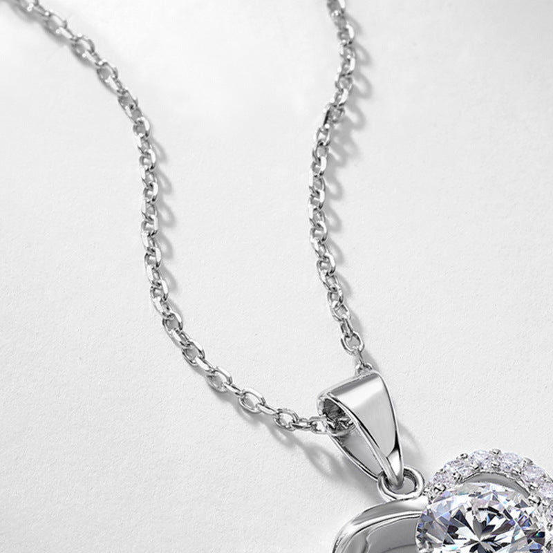 Angled close-up of round diamond floating heart pendant showing bail and half-pavé setting.