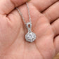 Close-up view of hand holding round diamond infinity knot halo pendant.