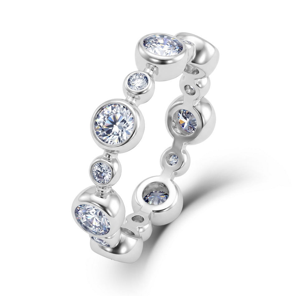 Angled profile view of round lab diamond bezel set bubble eternity band ring.