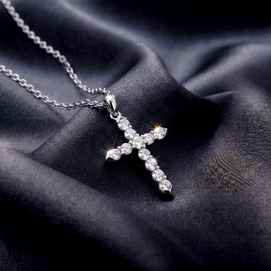 Perspective view of round cut lab diamond classic cross pendant necklace resting vertically on dark satin.