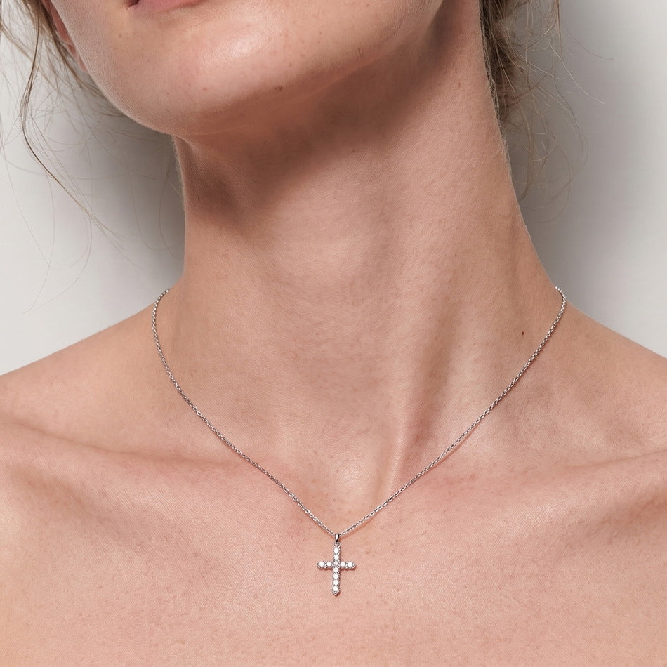 Close-up view of round lab diamond classic cross pendant necklace on collarbone.
