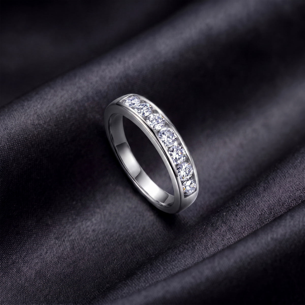 Perspective view of round lab-grown diamond channel set wedding band ring on dark silk.