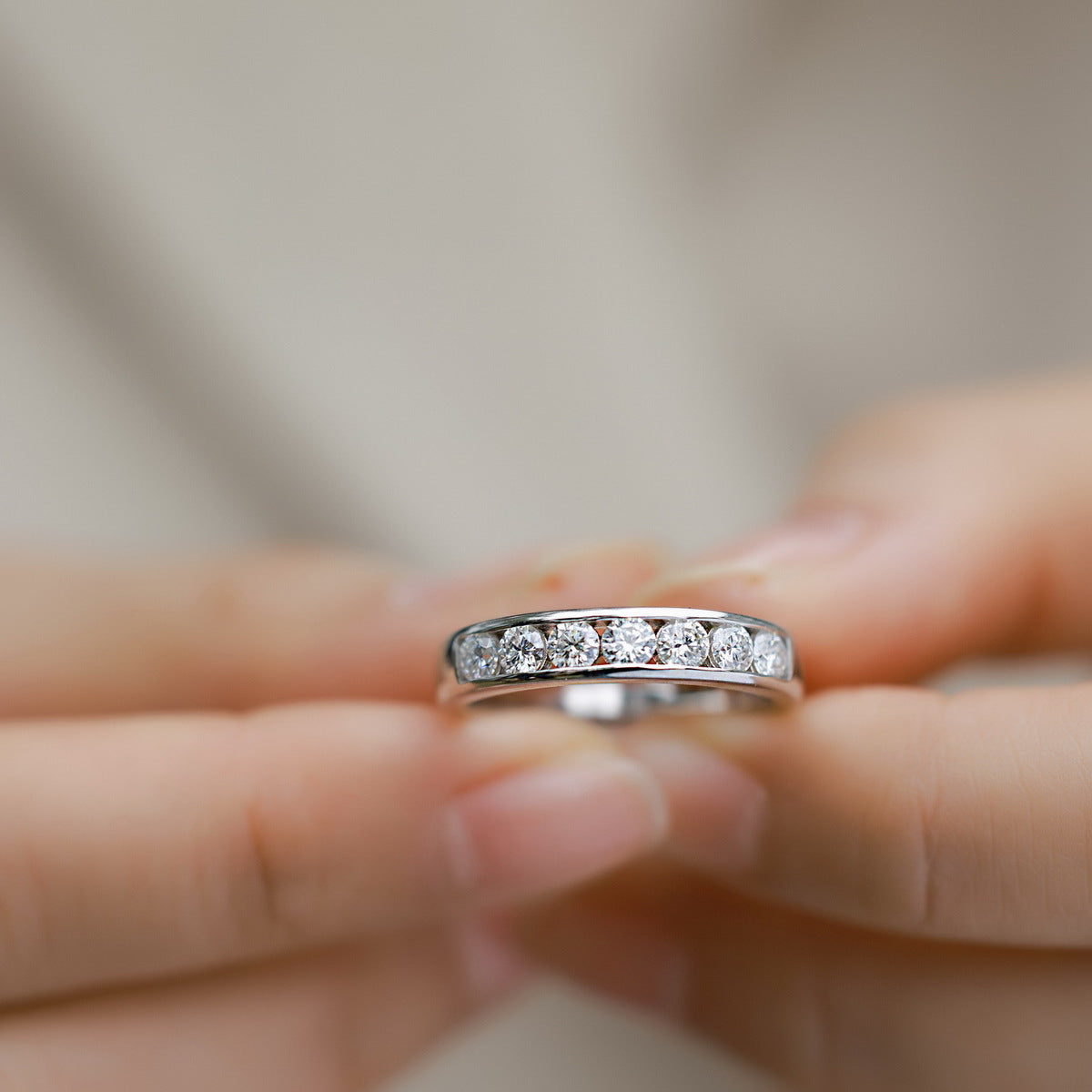 Close-up hand view of round lab-grown diamond channel set wedding band ring.