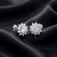 Perspective view of round lab-grown diamond floral halo stud earrings on dark silk background.