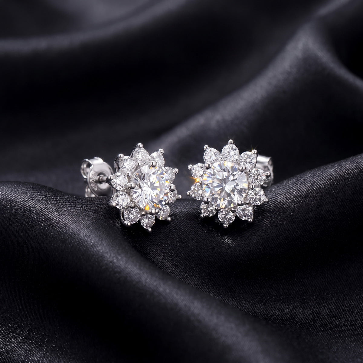 Perspective view of round lab-grown diamond floral halo stud earrings on dark silk background.