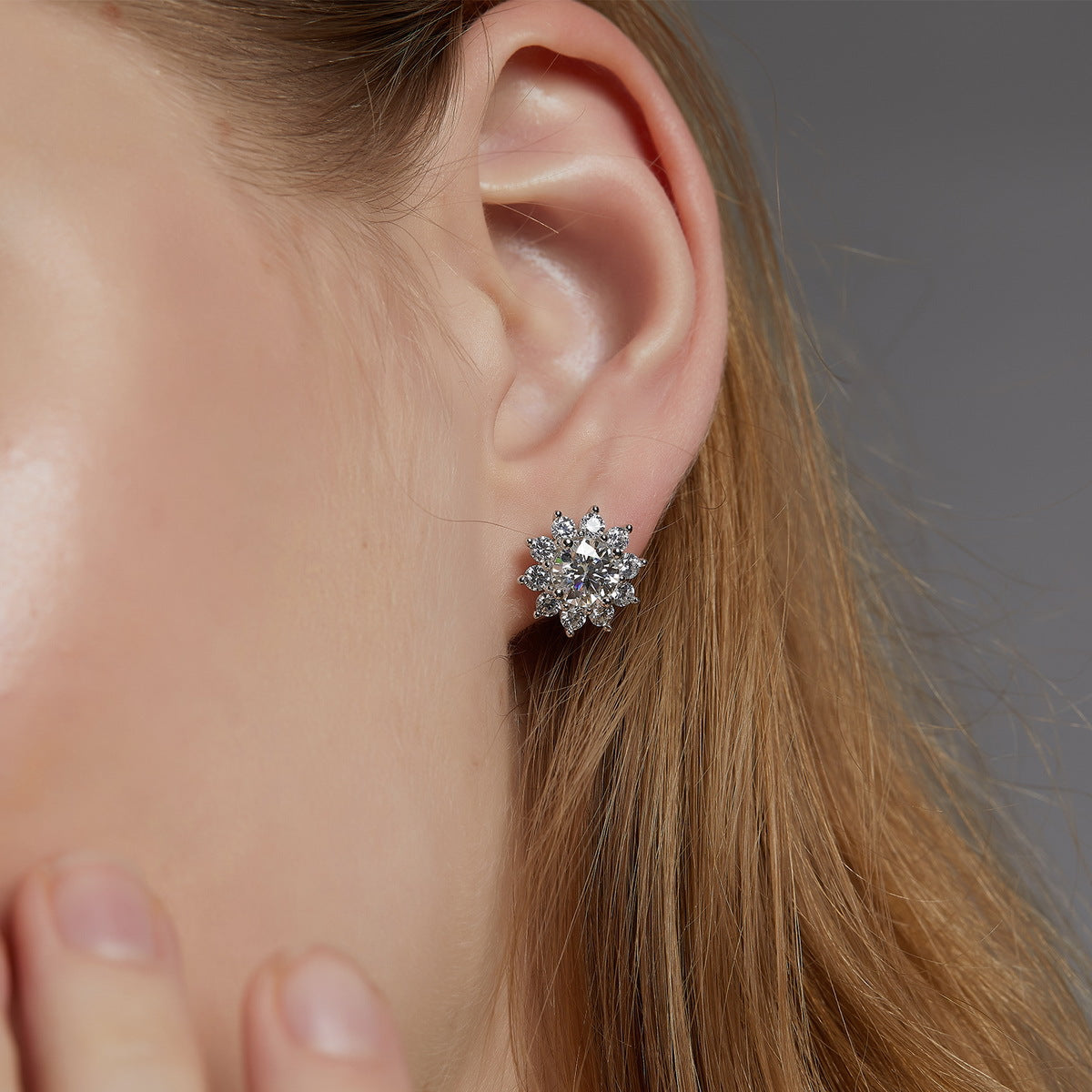 Model wearing round lab-grown diamond floral halo stud earrings.