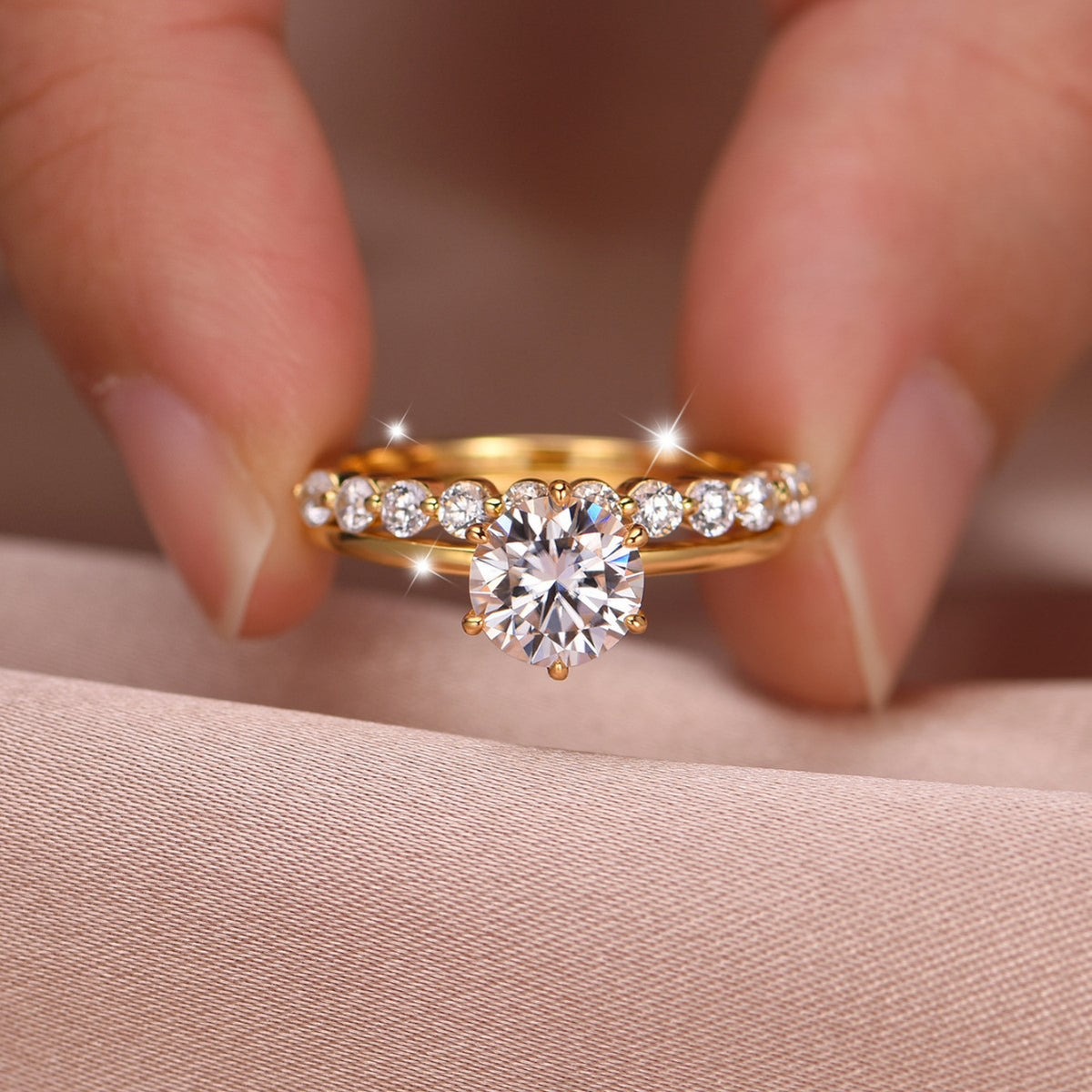 Close-up view of gold round moissanite crown solitaire with matching bubble stacking band held in hand.