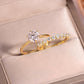 Angled shot of gold round moissanite crown solitaire and bubble band stacking set in box.
